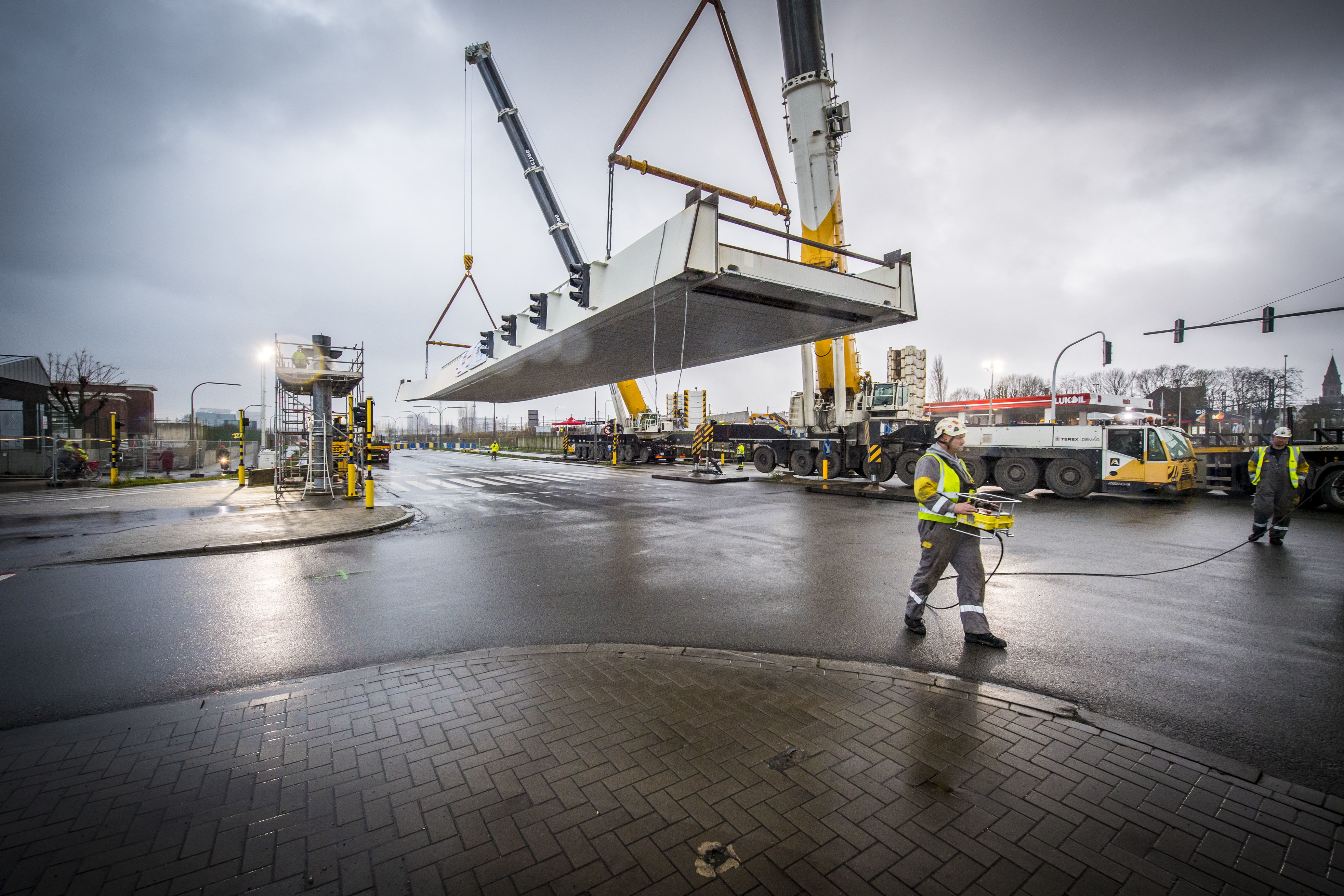 De twee kranen hijsen het eerste brugdeel op zijn plaats.