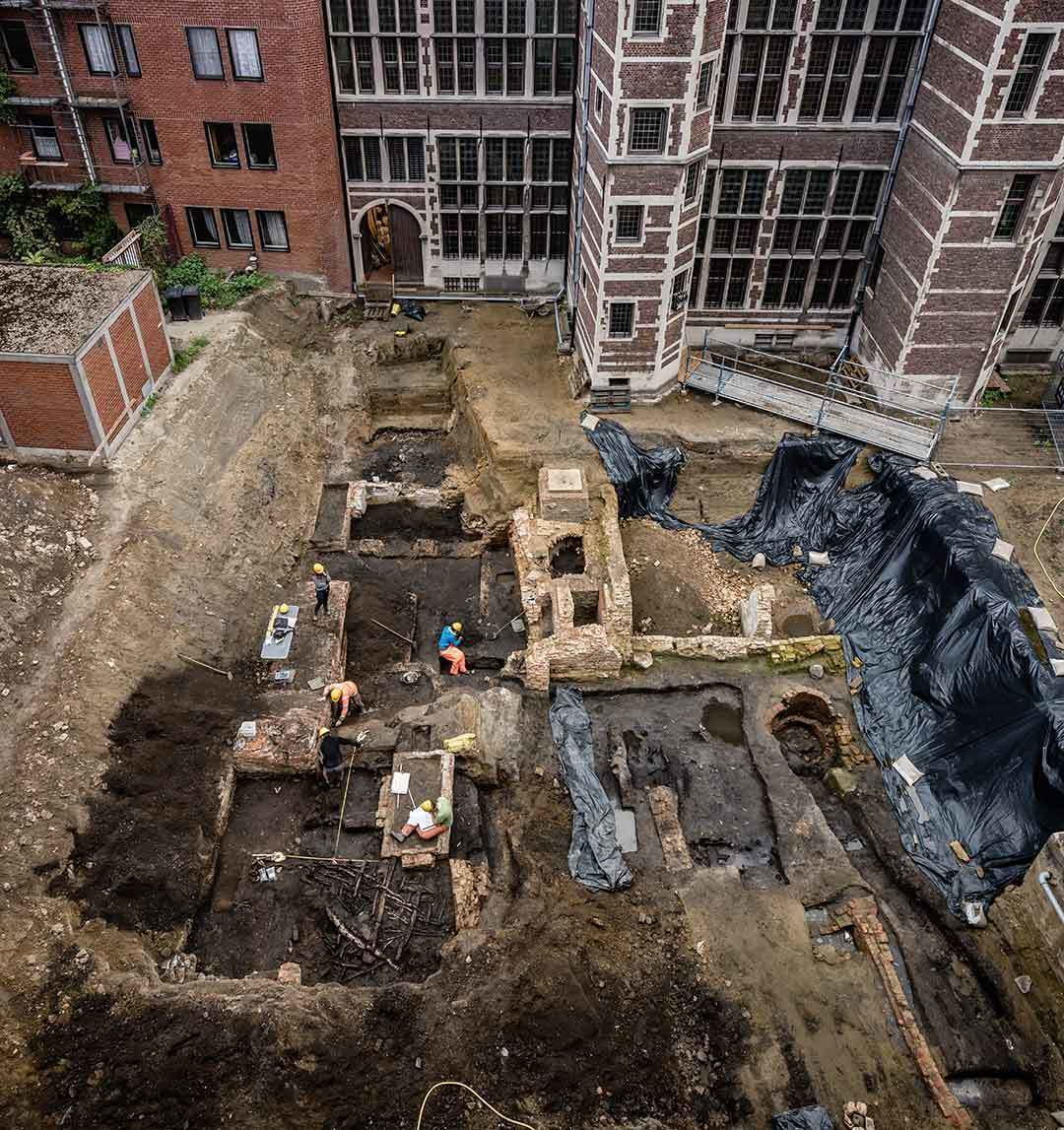 Zicht op de site zoals deze opengegraven is op 12 september 2019. De restanten uit de 15de eeuw bestaan uit kelders met vloeren in baksteen. Bepaalde muren vertonen een verkleuring van een brand die mogelijk verband houdt met de Spaanse Furie van 1576. De meest donker gekleurde vlakken bevatten houten palen, riet, vlechtwerk en een omgevallen wand uit de 13de eeuw. Dat het hout zo goed bewaard is gebleven, is een verrassing. Dit zal ons veel leren over de bewoning in die periode. Rechts onderaan zijn nog diepere lagen onderzocht, die houten structuren vertonen uit de 12de eeuw. Toen Antwerpen nog de Ruienstad werd genoemd.