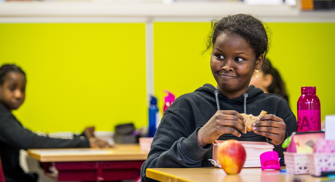 Kind geniet van een boterham en appel tijdens lunch in de klas.