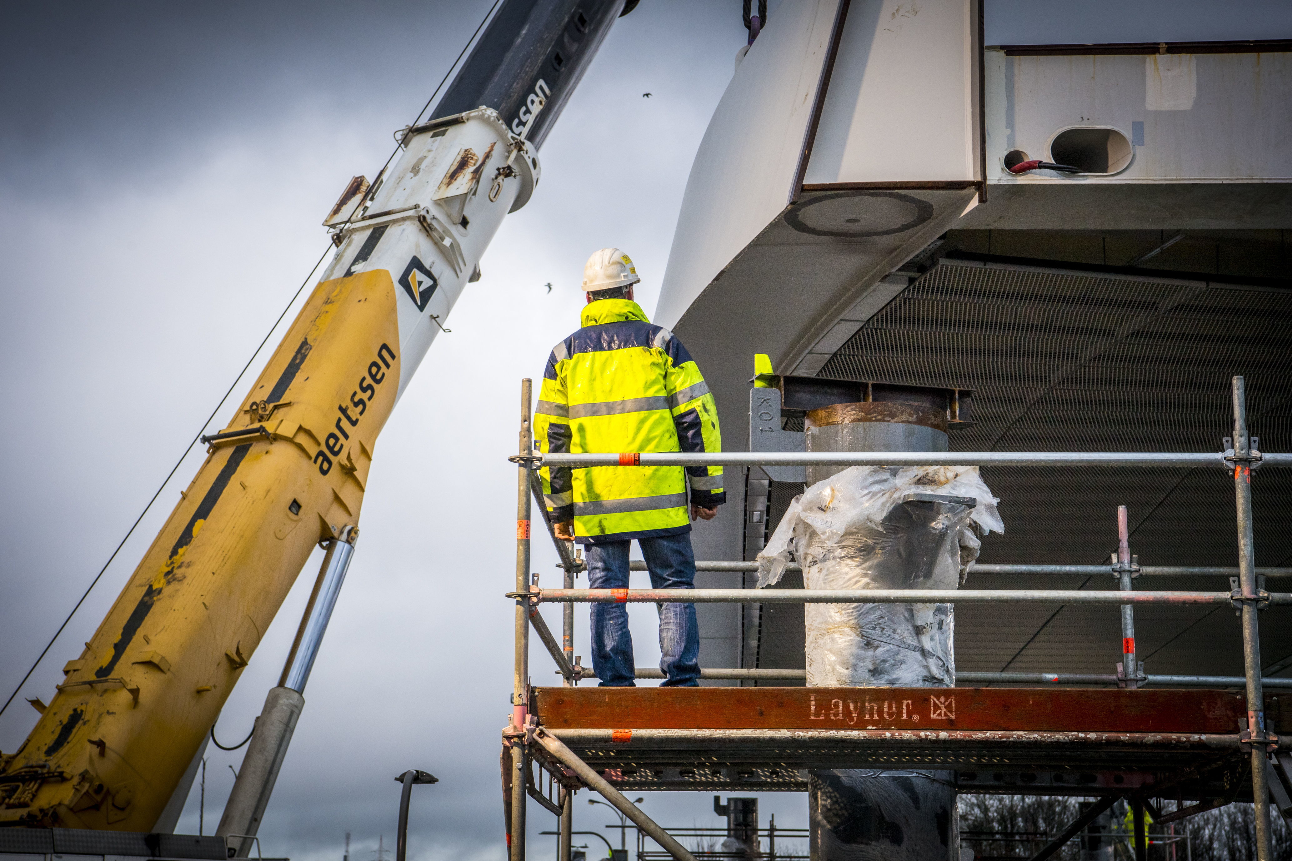 De twee kranen hijsen het eerste brugdeel op zijn plaats.