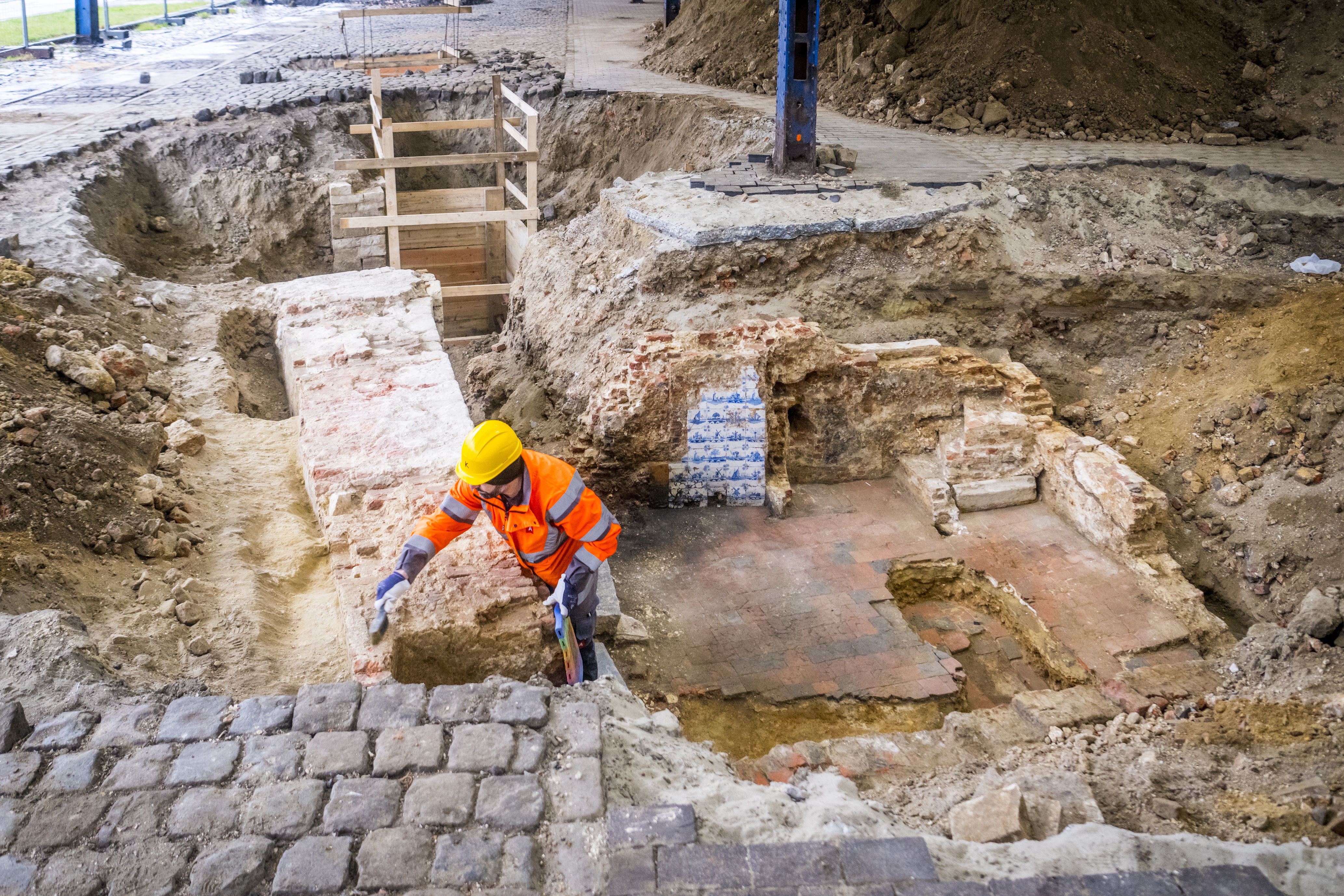 Overzicht stadsmuur met het havenhuis tegen gebouwd en achteraan de Kleine Bierpoort. In het huisje zijn de blauwe Delftse tegels van de haard te zien. De muur wordt proper gemaakt met een borstel.