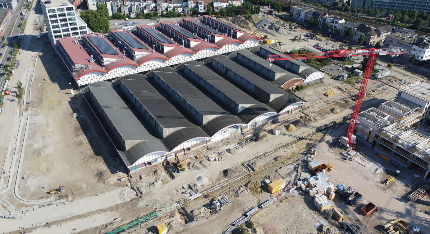 Een luchtbeeld van eind juni waarop de basis voor de Twee Stierenstraat, de nieuwe hoofdtoegang tot de wijk, al goed zichtbaar is langs een van de voormalige slachthuishallen