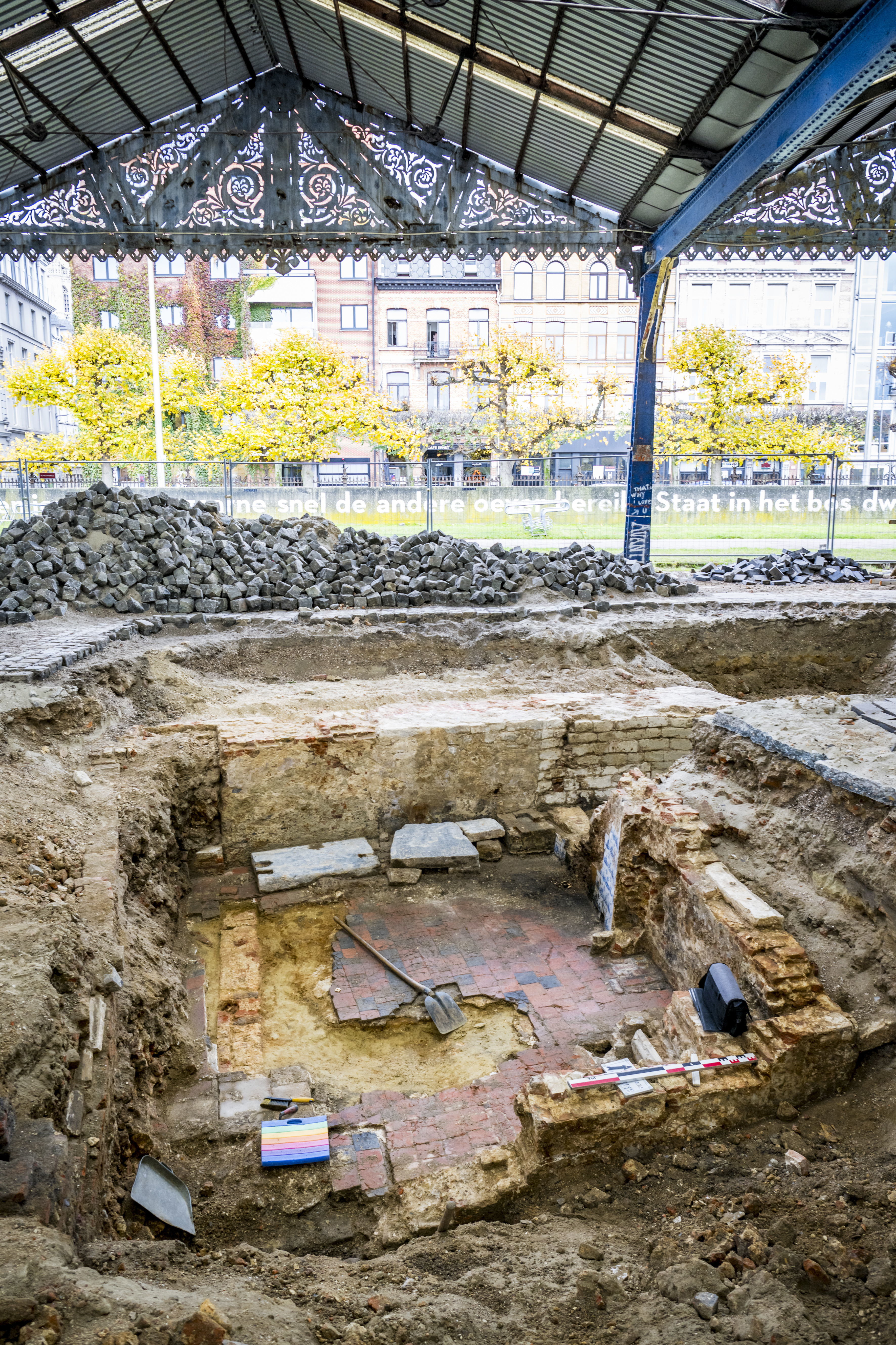 Overzicht van het havenhuis gebouwd tegen de stadsmuur aan de Kleine bierpoort, met het materiaal van de archeologen verspreid over de werkput. Achteraan is de stadsmuur te zien in witte natuursteen.
